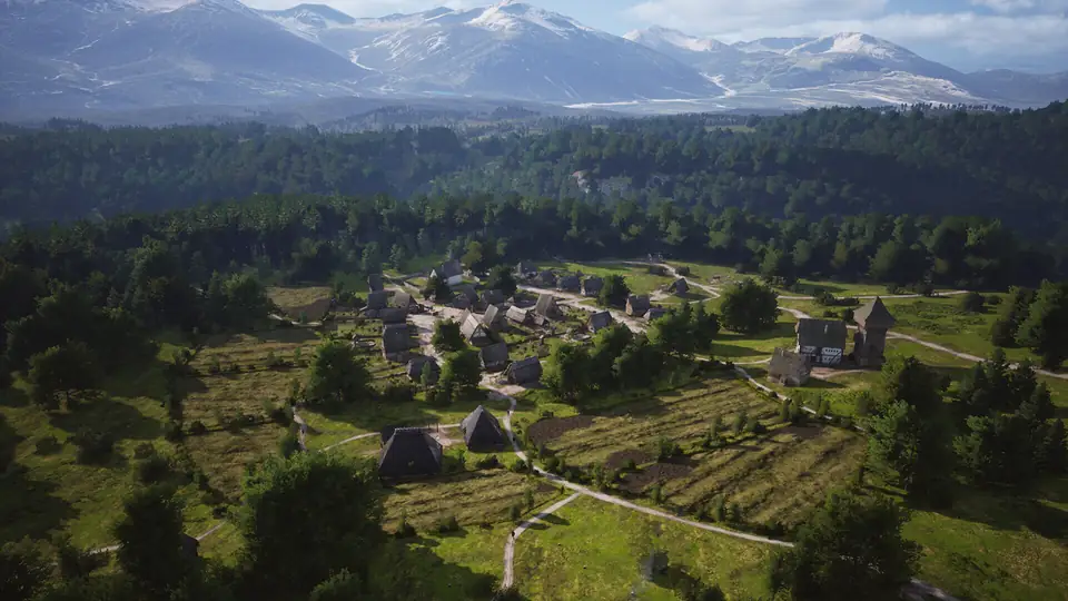 A village strung along a road in a wide valley, with strip fields between the houses and the forest.